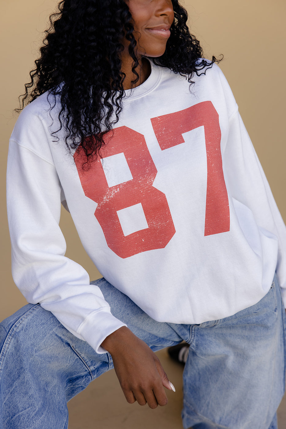 a woman wearing a white sweatshirt with a red number on it