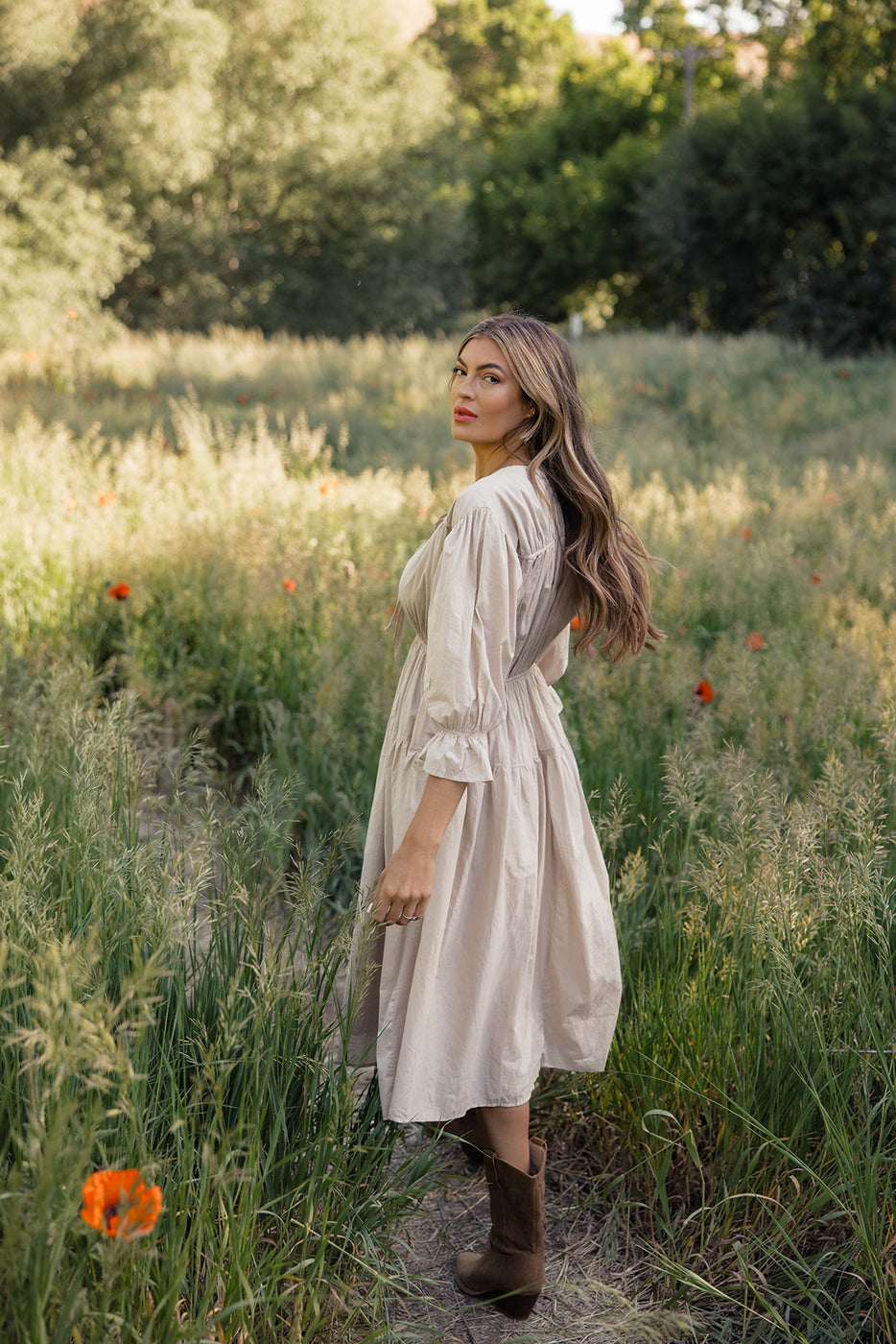 a woman in a dress standing in a field of tall grass