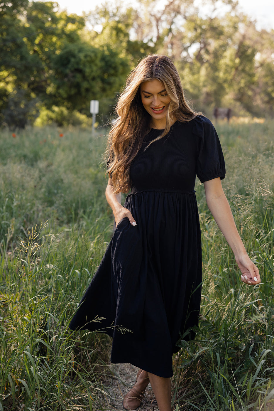 a woman in a black dress in a field of tall grass