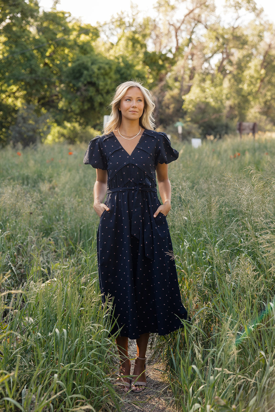 a woman in a dress standing in tall grass