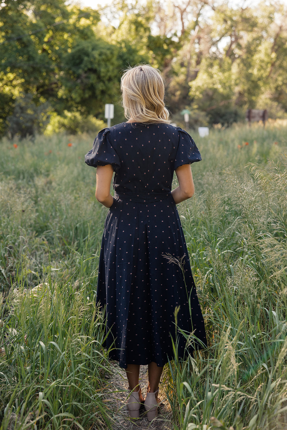 a woman in a dress standing in tall grass