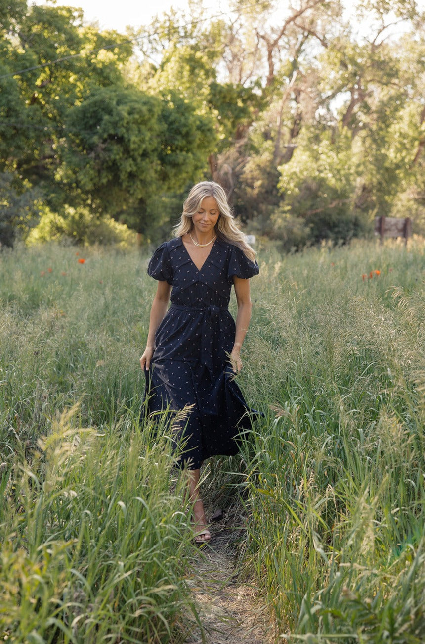 a woman in a dress walking through tall grass