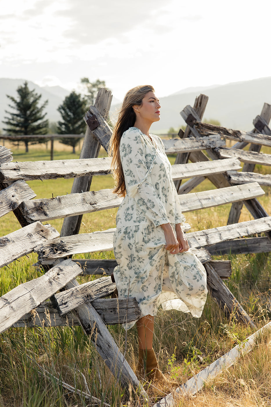 a woman in a white dress standing in front of a broken fence