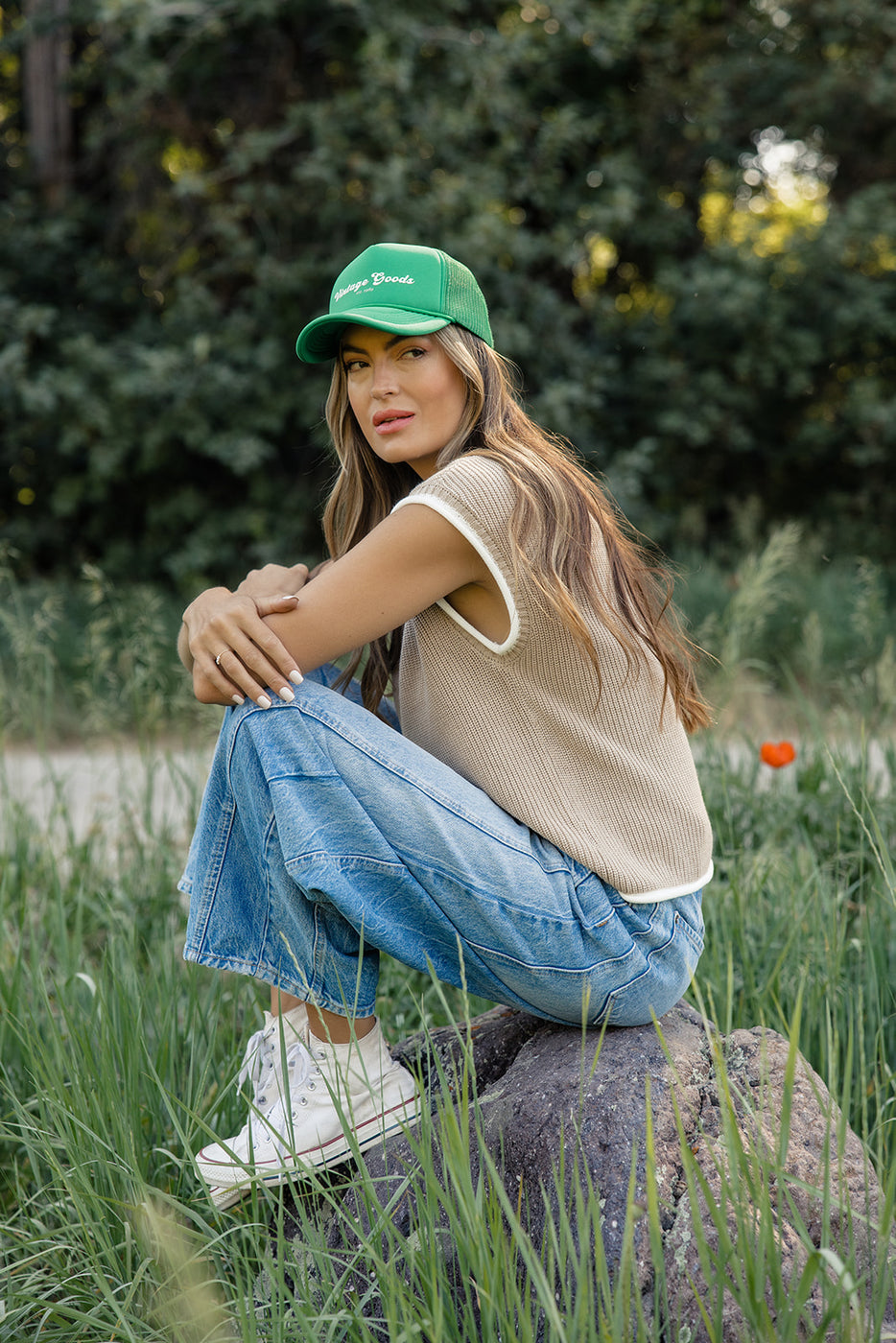 a woman sitting on a rock in a field of tall grass