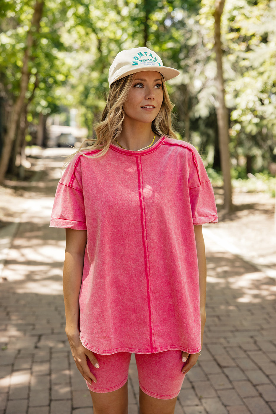 a woman wearing a hat and pink shirt