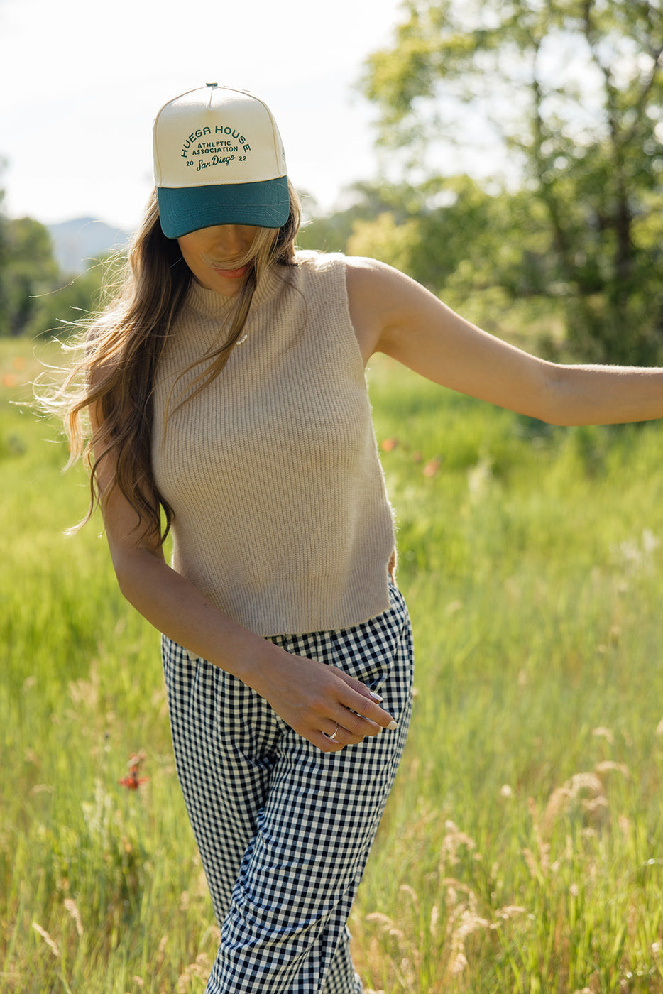 a woman wearing a hat and standing in a field