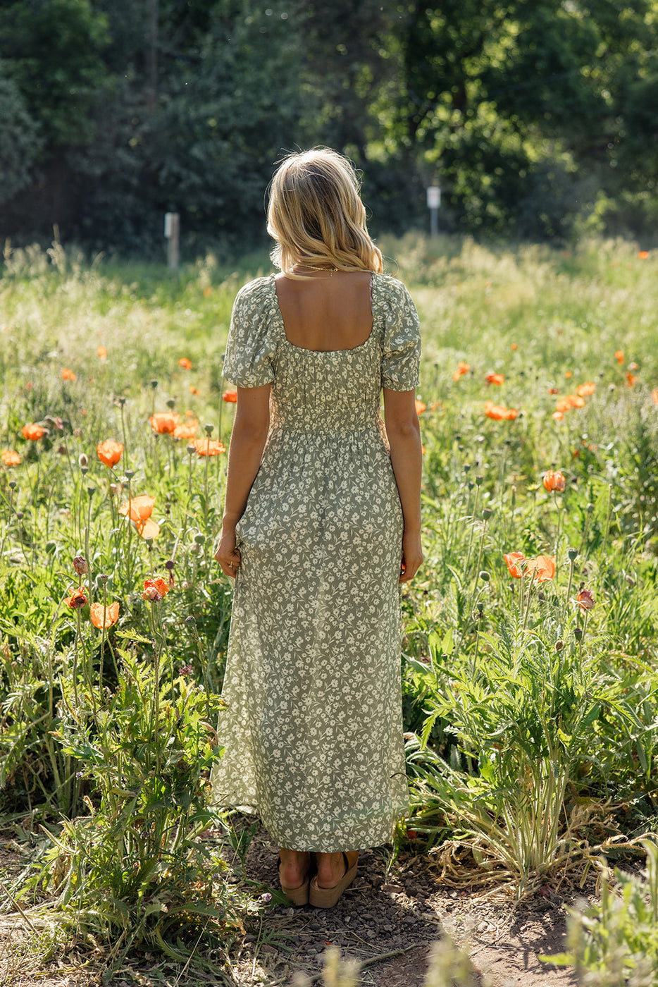 a woman in a dress standing in a field of flowers