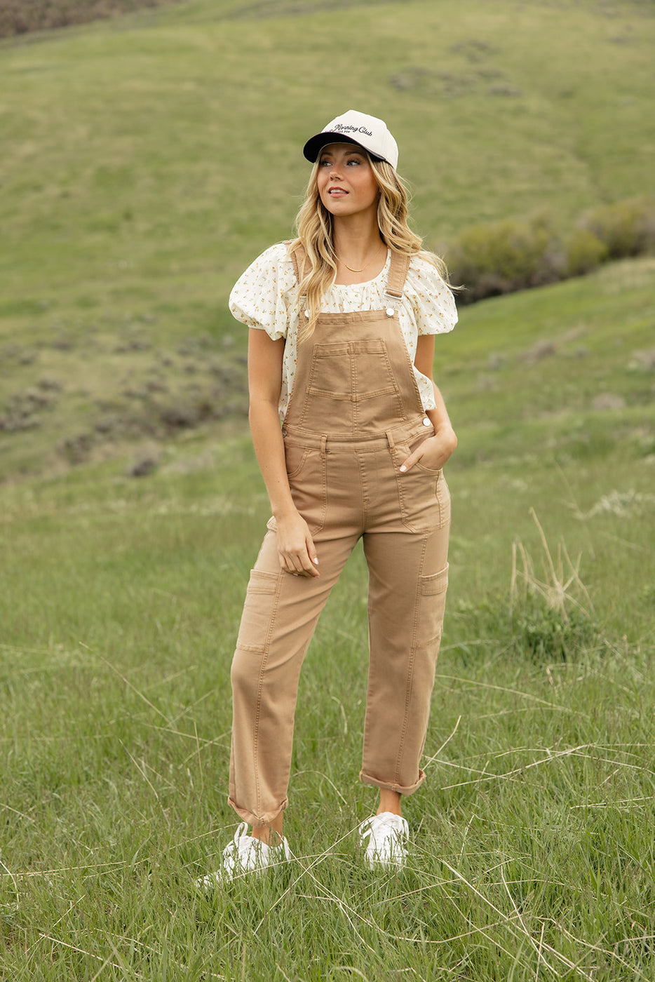a woman in overalls standing in a field