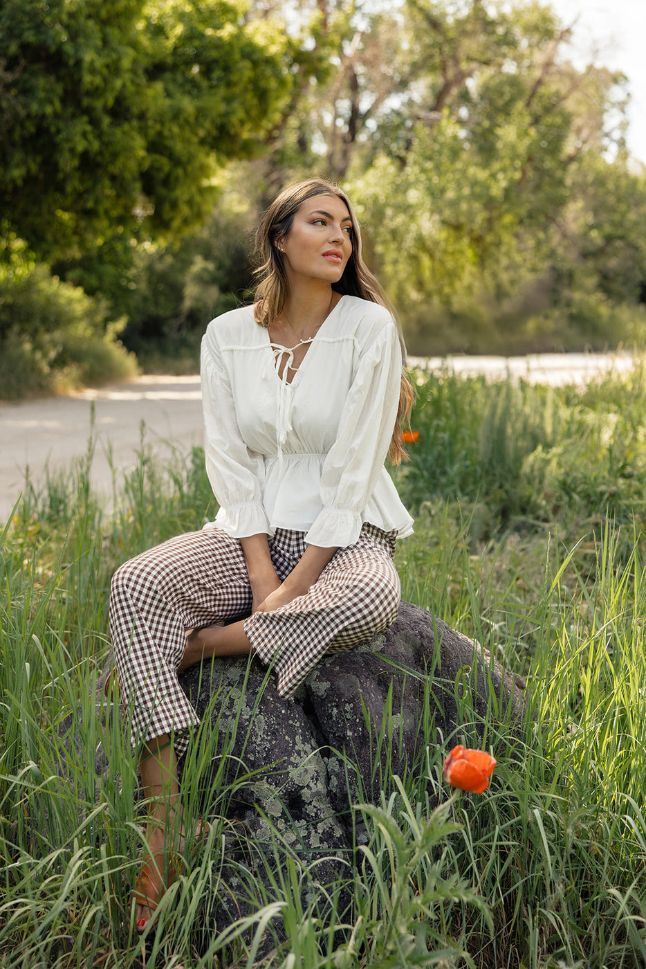 a woman sitting on a rock in tall grass