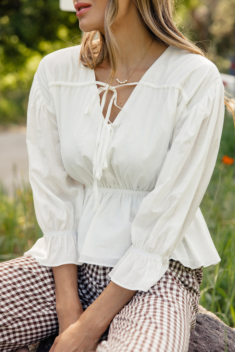 a woman sitting outside in a white shirt