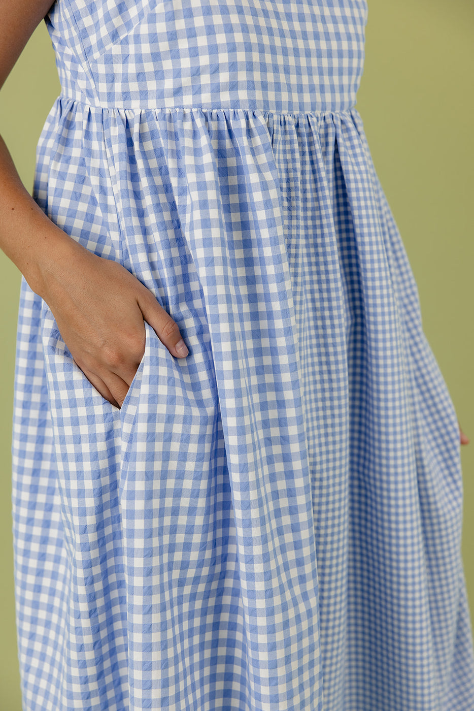 a hand in a blue and white checked skirt