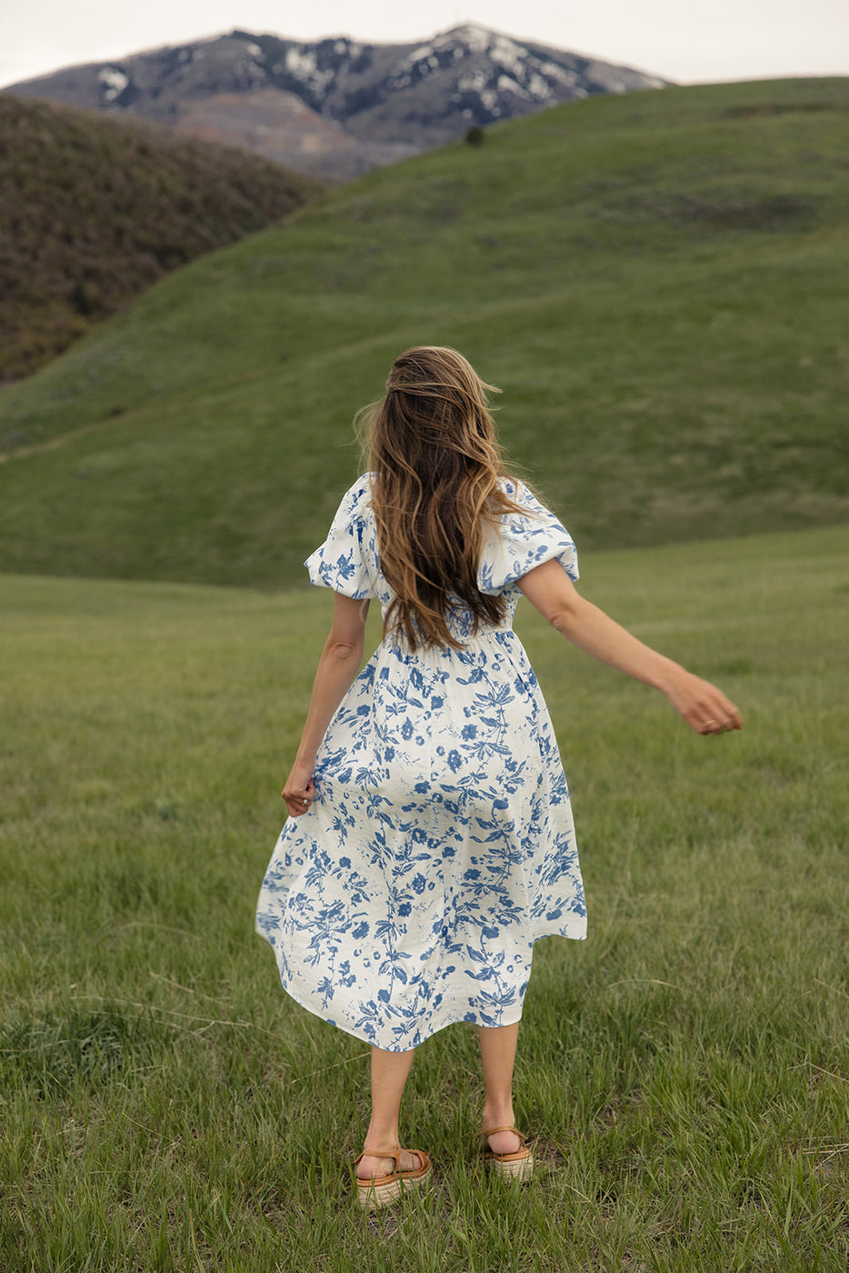 a woman in a dress walking in a grassy field
