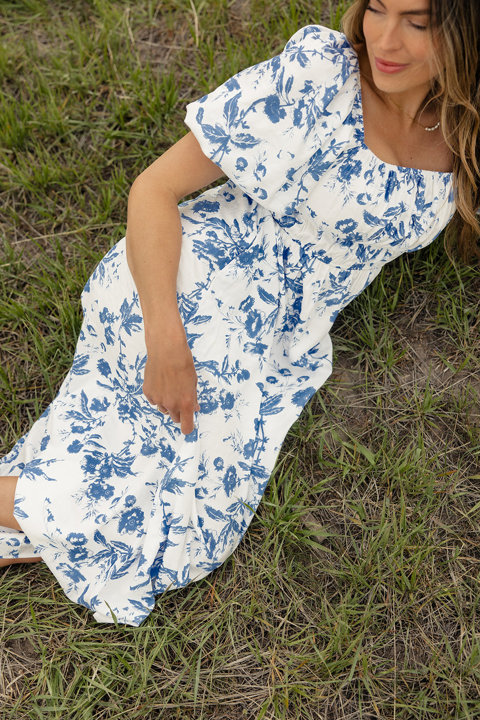 a woman in a white and blue dress lying on grass