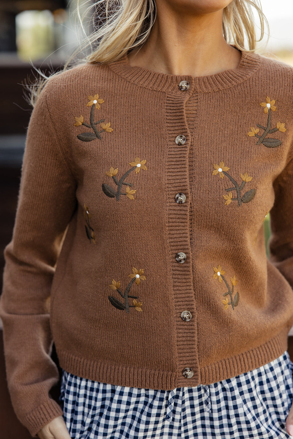 a woman wearing a brown sweater with flowers on it