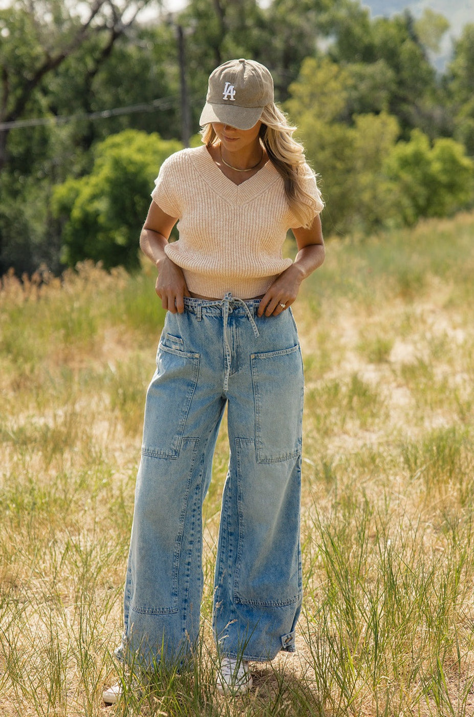 a woman wearing a hat and wide leg jeans