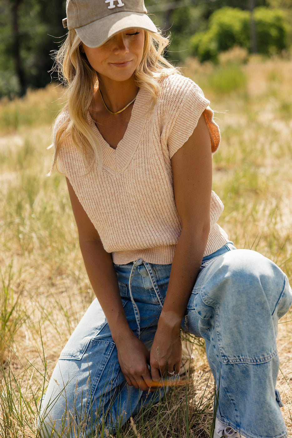 a woman in a hat squatting in a field