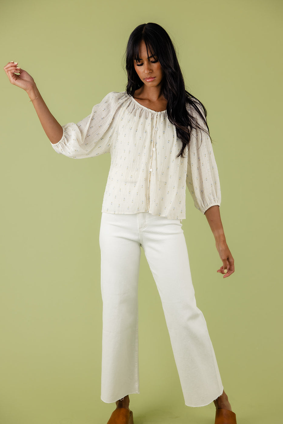 a woman in white pants and white blouse holding up a green background