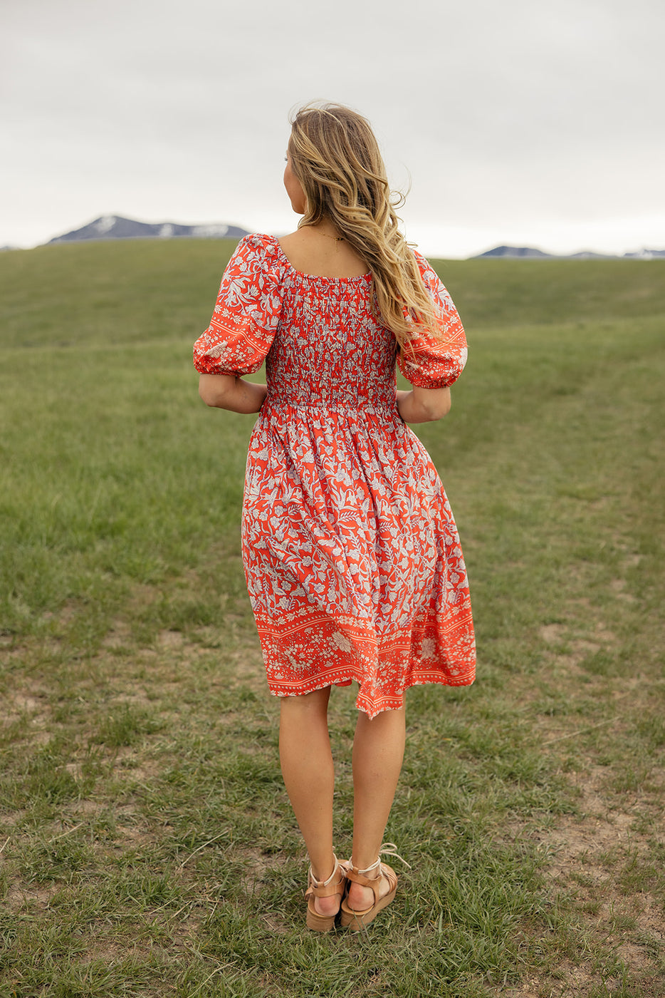 a woman in a red dress standing in a field
