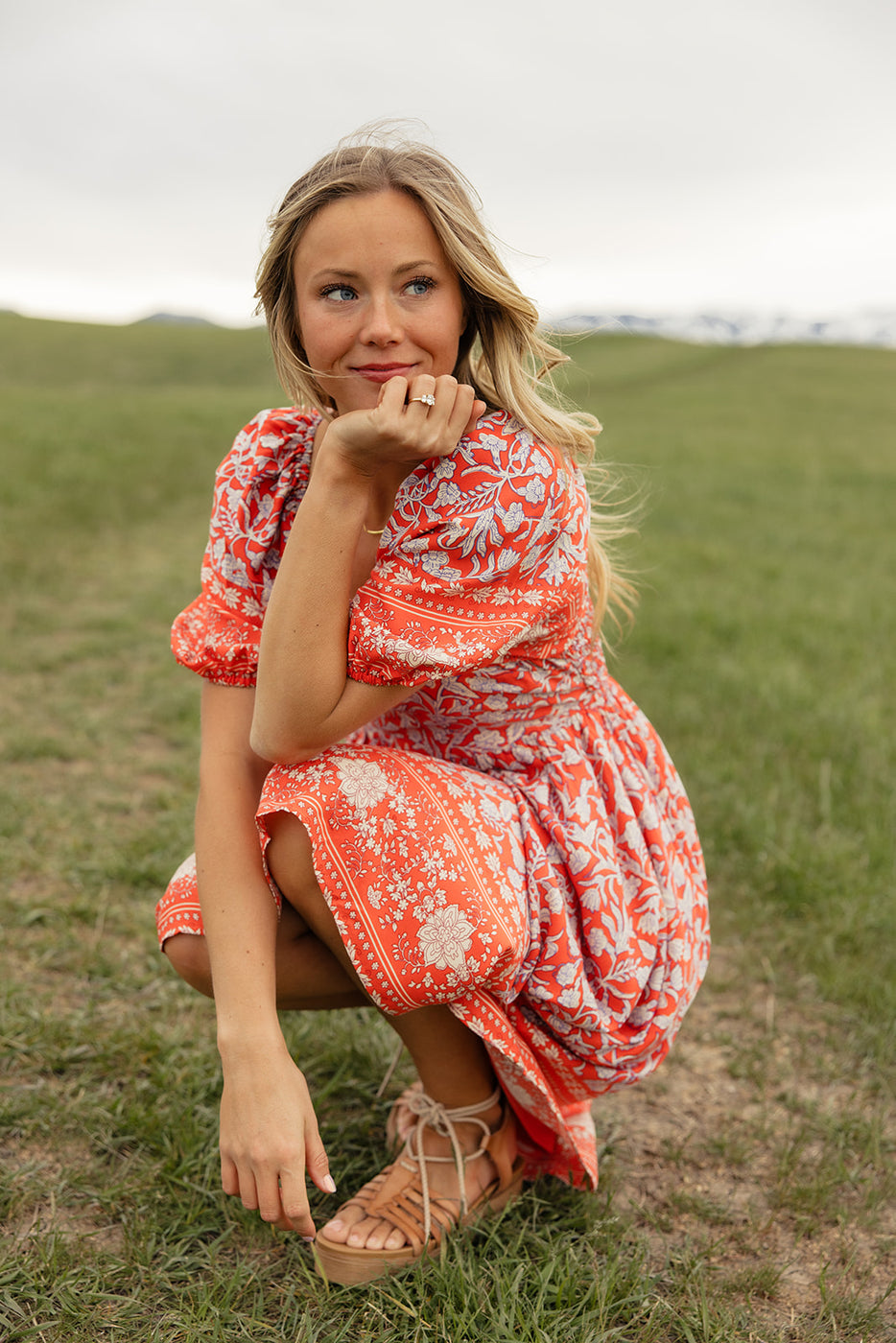 a woman in a dress squatting in a field