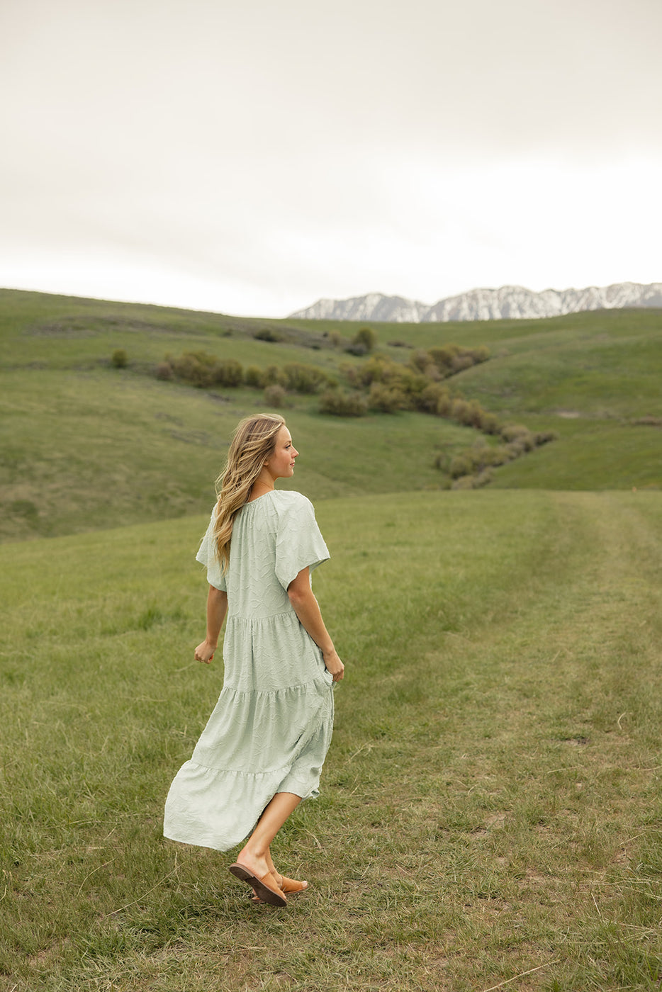 a woman in a dress walking in a grassy field