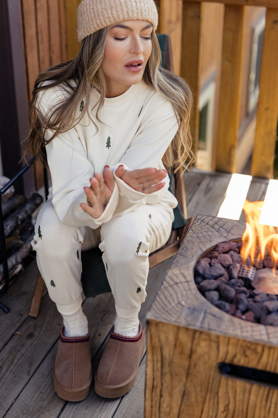 a woman sitting on a porch with her hands in front of a fire