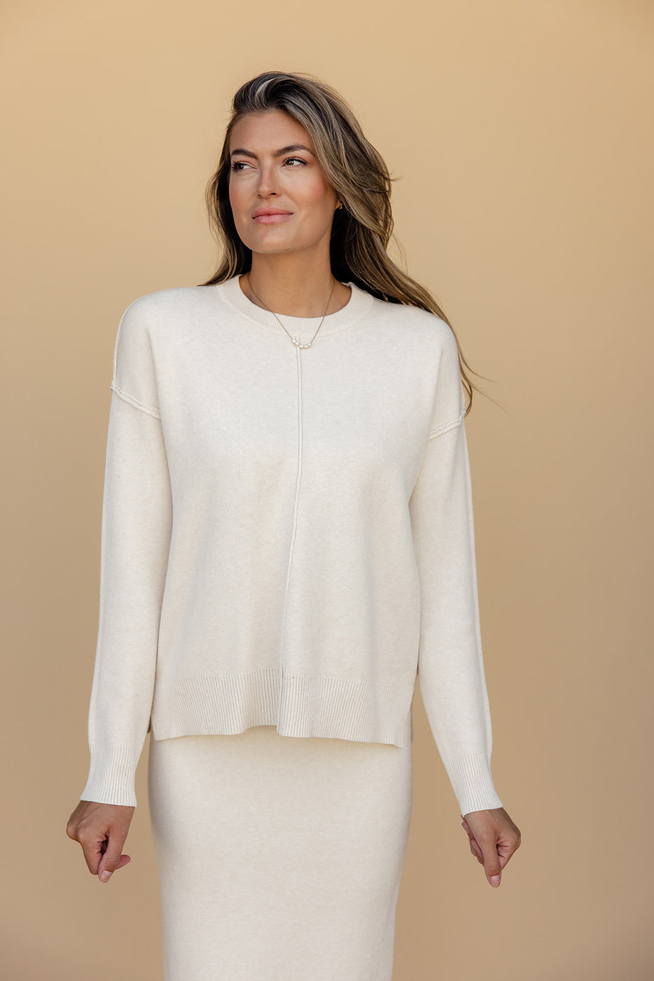 a woman in a white sweater and skirt