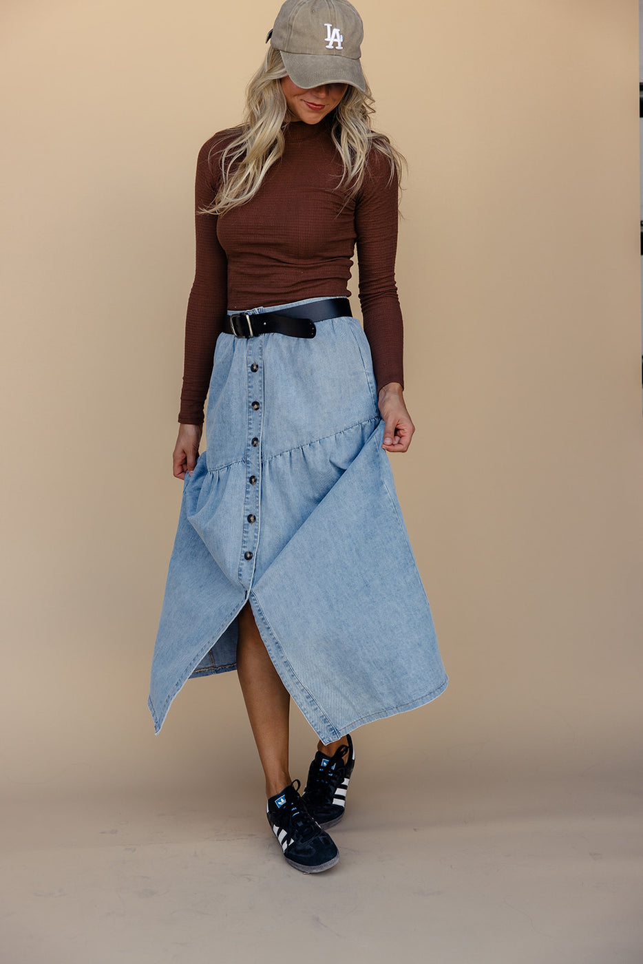 a woman wearing a long sleeved shirt and a blue skirt