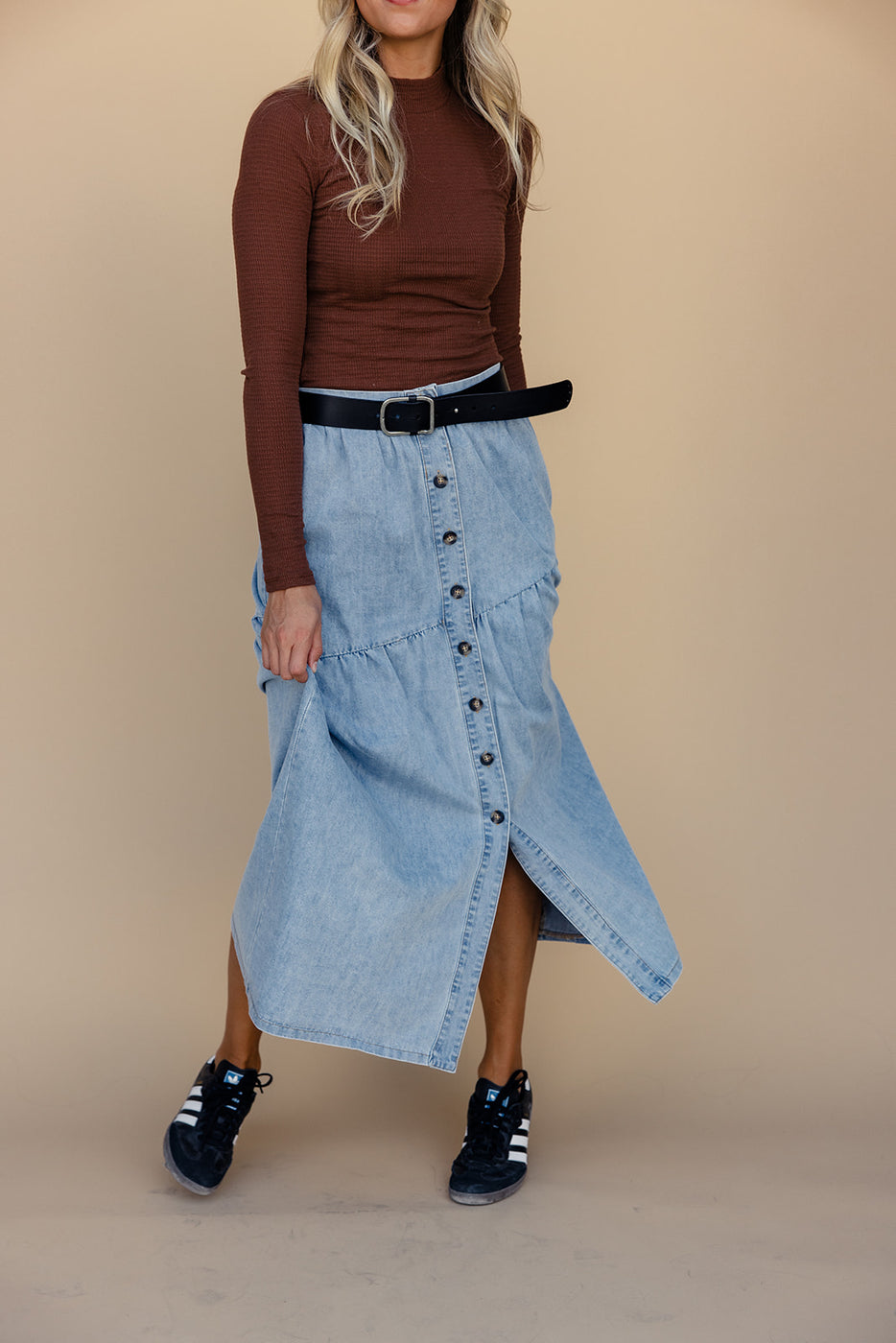 a woman wearing a skirt and a brown shirt