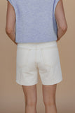 Person wearing light-colored shorts and a sleeveless top on a beige background