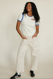 Woman wearing a graphic tee and white pants with black sneakers