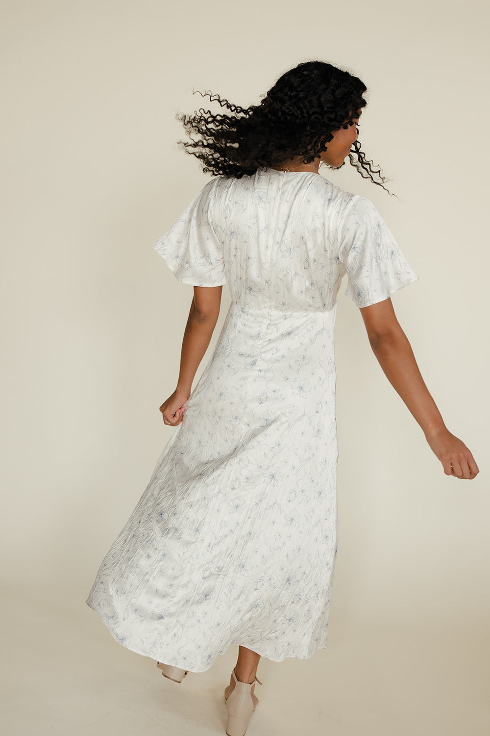 Woman wearing a white dress with a subtle pattern on a beige background