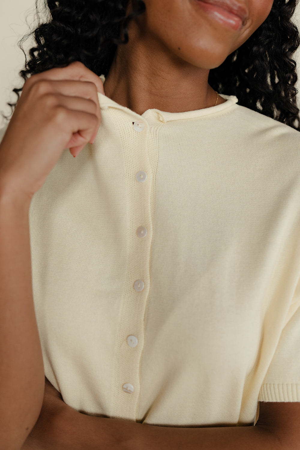 Woman wearing a cream-colored cardigan with a close-up of the neckline.