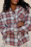 Person wearing a plaid shirt with rolled-up sleeves against a neutral background