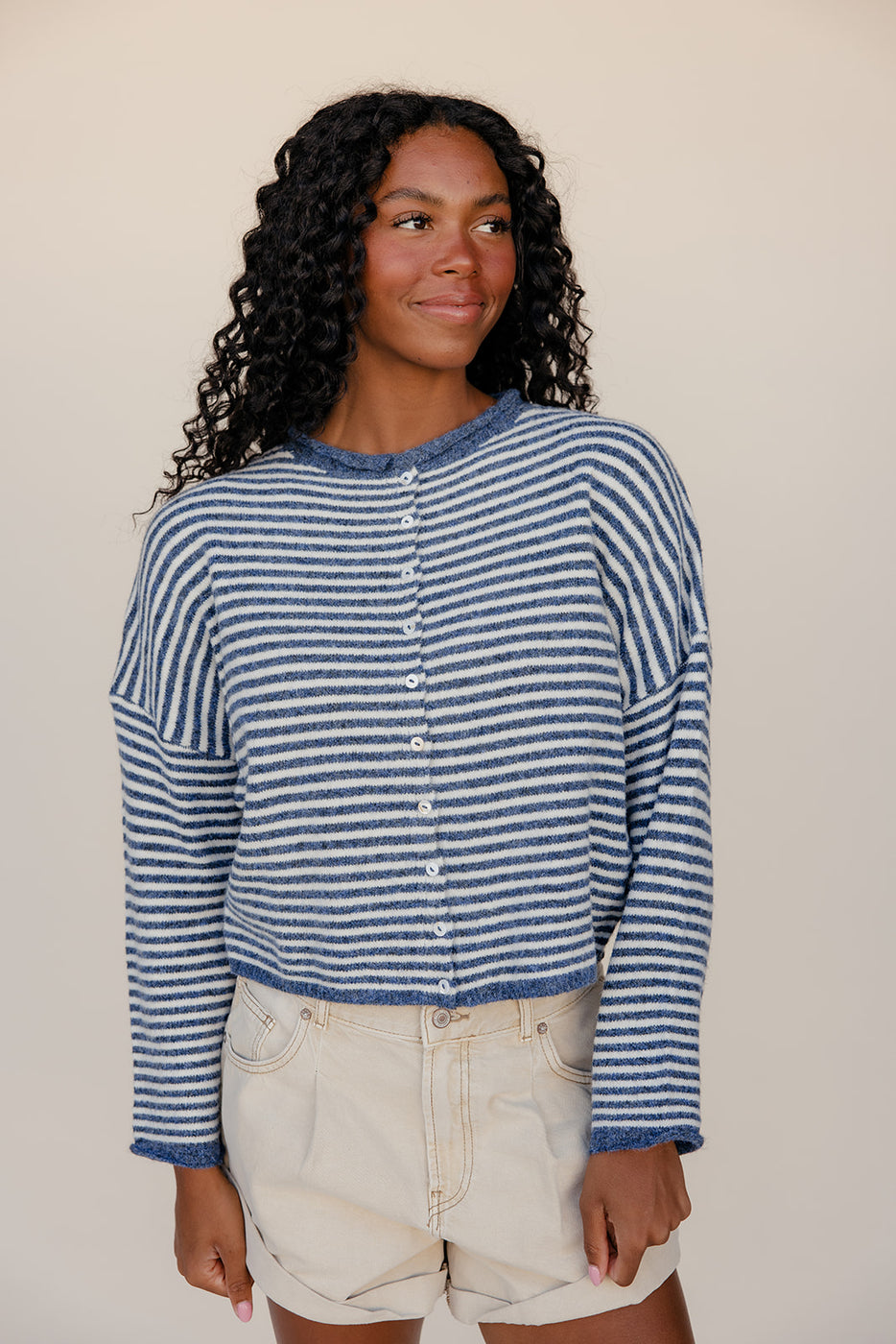 Woman wearing a blue and white striped shirt against a plain background