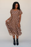 Woman wearing a brown floral dress with black boots on a white background