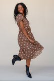 Woman wearing a brown floral dress with black boots on a white background