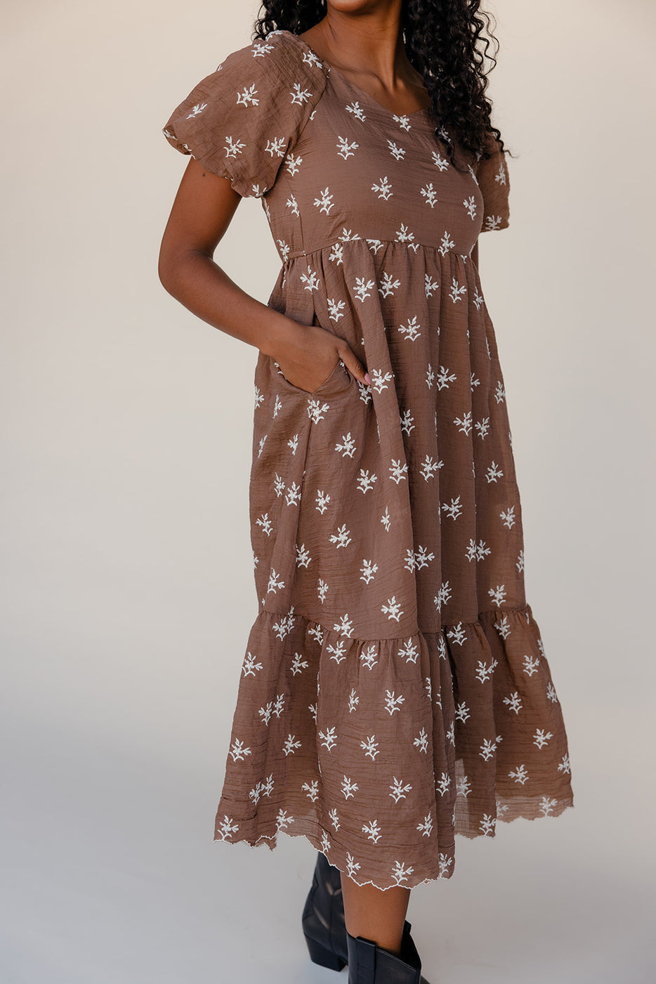 Woman wearing a brown floral dress against a white background