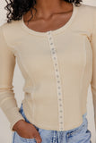 Beige long-sleeve top with button details worn by a person, against a neutral background