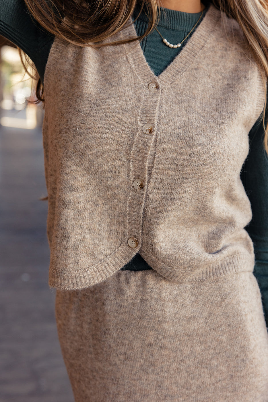 a woman wearing a sweater vest and skirt