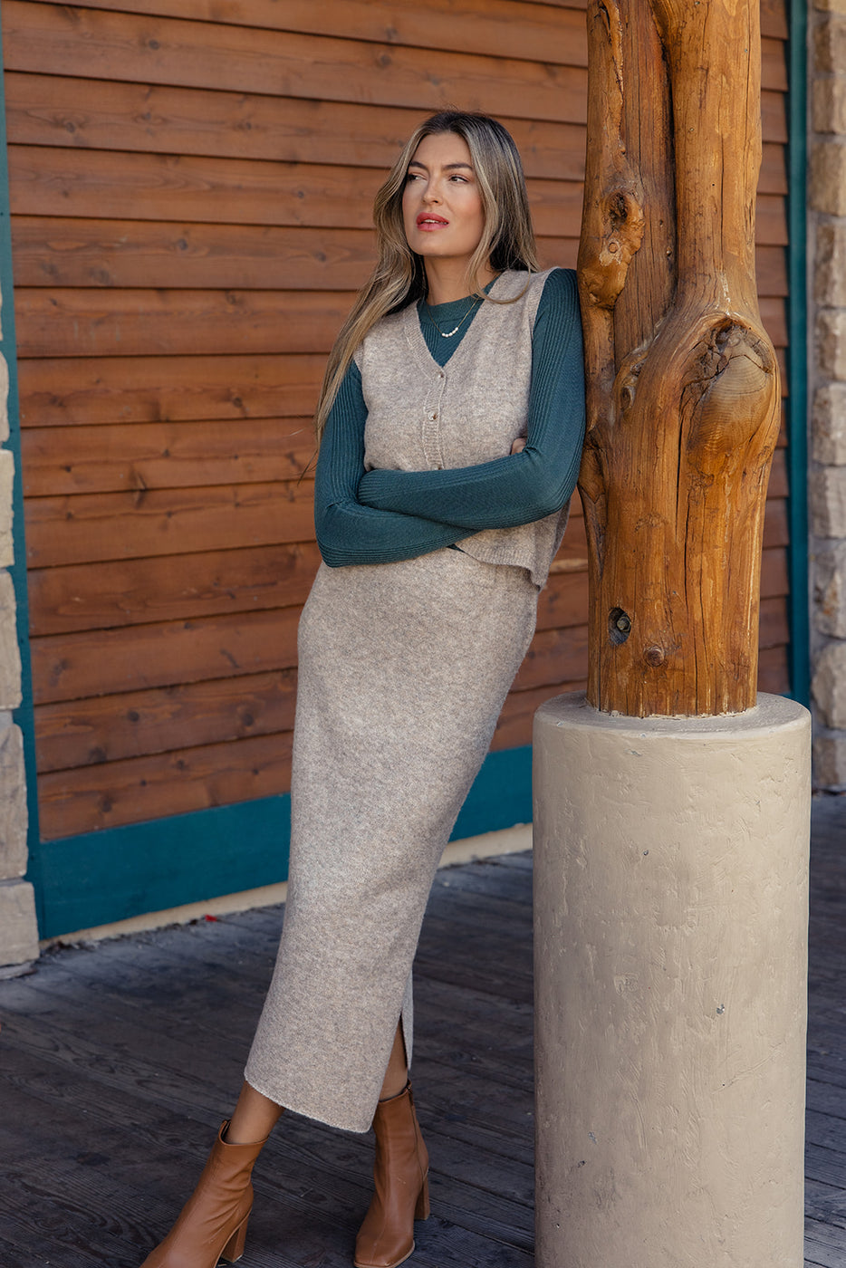 a woman leaning against a wooden pole