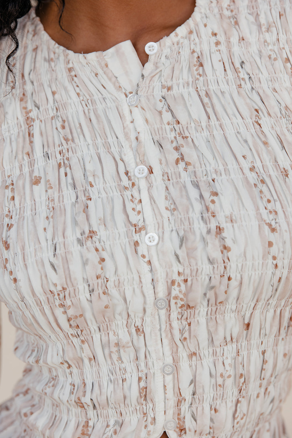 Close-up of a textured beige and brown patterned garment with buttons.