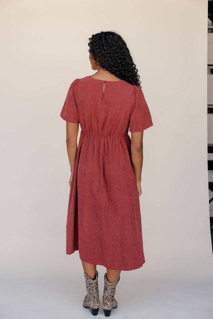 Person wearing a red dress with a plain background