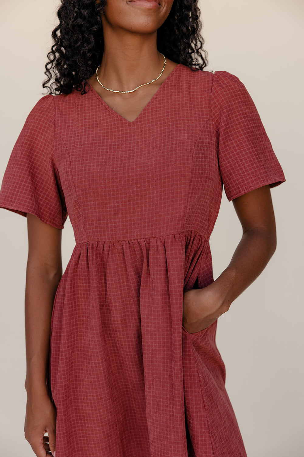 Woman wearing a red checkered dress against a neutral background
