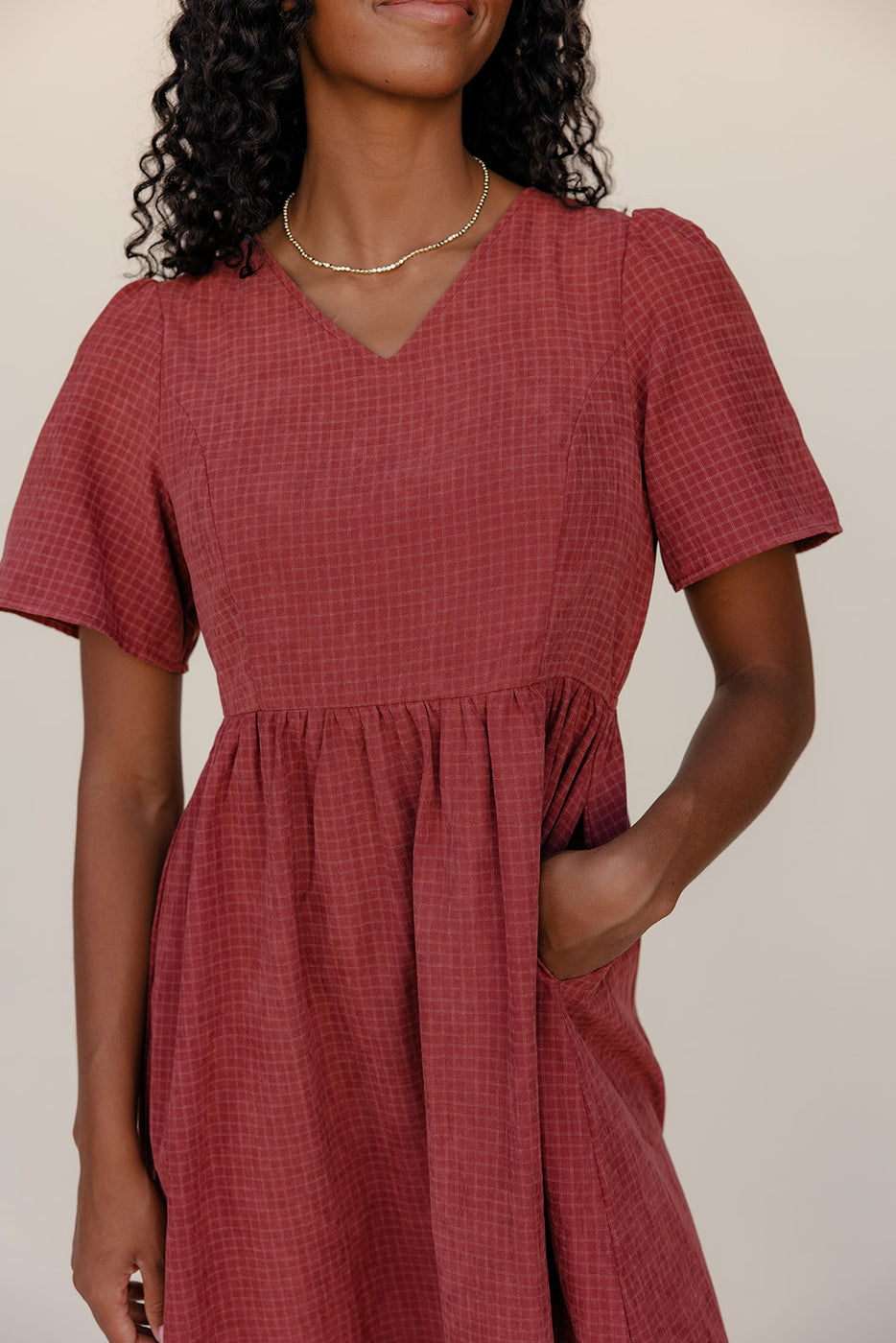 Woman wearing a red checkered dress against a neutral background