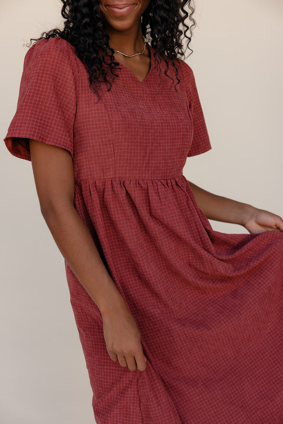 Woman wearing a red checkered dress against a plain background