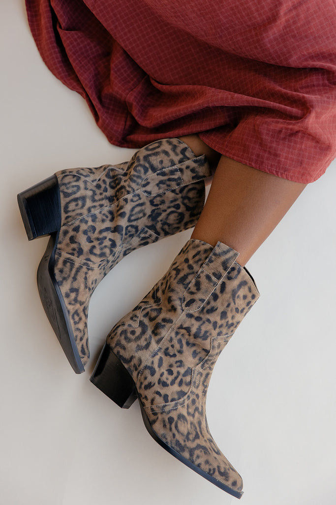 Leopard print boots worn with a red skirt on a white background