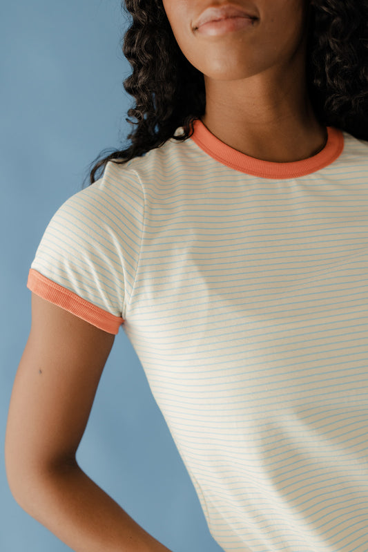 Person wearing a white and orange striped shirt against a blue background