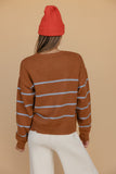 Person wearing a brown striped sweater and red beanie on a beige background