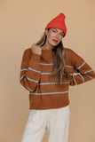Woman wearing a brown striped sweater and red beanie against a beige background
