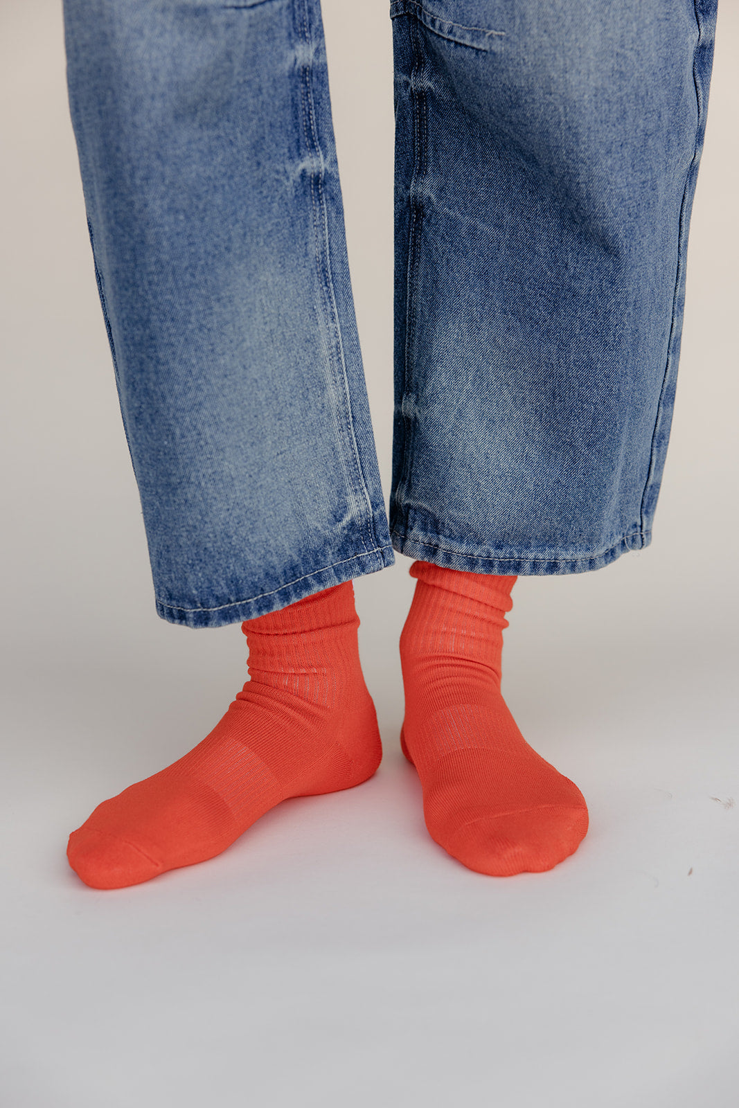 Person wearing bright red socks and blue jeans on a white background